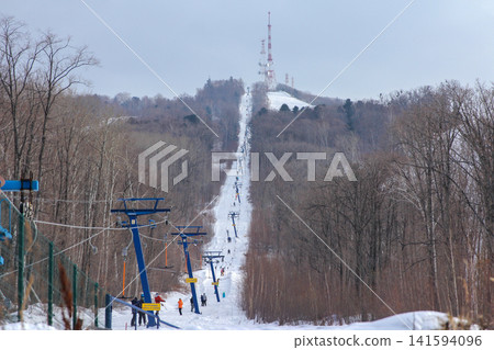 Russia Primorsky Krai Arsenyev 20 January 2026. Ski lift going up the mountain with TV tower on top. Winter sports tourism infrastructure at ski resort in Far East Russia Primorsky Krai Arsenyev 20 January 2026. Ski lift going up the mountain with TV tower on top. Winter sports tourism infrastructure at ski resort in Far East 141594096