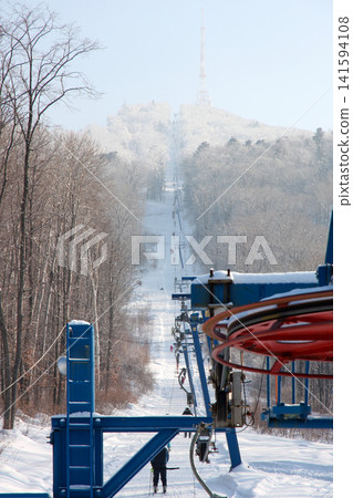 Russia Primorsky Krai Arsenyev 20 January 2026. Ski lift going up the mountain with TV tower on top. Winter sports tourism infrastructure at ski resort in Far East Russia Primorsky Krai Arsenyev 20 January 2026. Ski lift going up the mountain with TV tower on top. Winter sports tourism infrastructure at ski resort in Far East 141594108