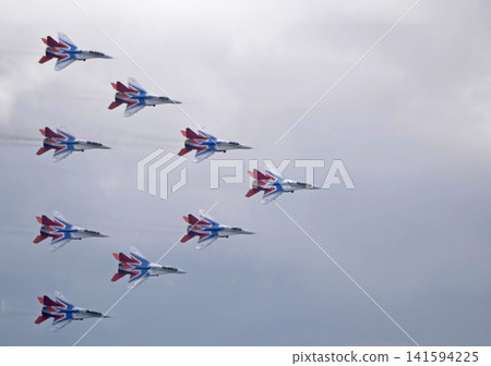 Russia Kubinka 12 April 2025. Strizhi aerobatic team performing on MiG-29 fighter jets during an air show. Russian military aircraft in formation flight with smoke trails against blue sky Russia Kubinka 12 April 2025. Strizhi aerobatic team performing on MiG-29 fighter jets during an air show. Russian military aircraft in formation flight with smoke trails against blue sky 141594225