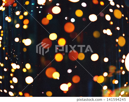 Abstract glowing bokeh lights reflected on rain covered glass at night. Warm golden circles create an atmospheric festive background with dreamy defocused illumination and urban mood. 141594245