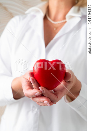 A Compassionate Woman in a White Lab Coat Cradling a Heart Symbol Reflecting Care and Dedication A Compassionate Woman in a White Lab Coat Cradling a Heart Symbol Reflecting Care and Dedication 141594322