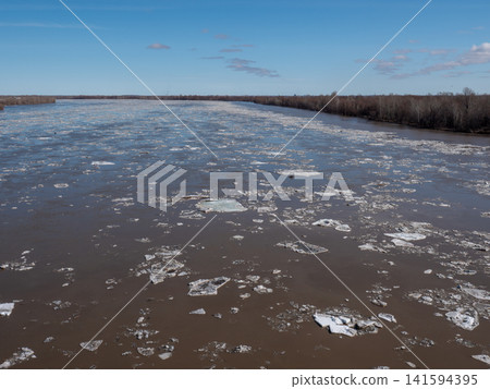 River with ice drift in spring blue sky with light clouds natural landscape flowing water seasonal thaw and nature scenery. River with ice drift in spring blue sky with light clouds natural landscape flowing water seasonal thaw and nature scenery. 141594395