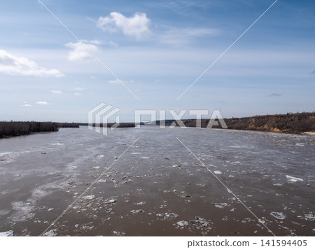 River with ice drift in spring blue sky with light clouds natural landscape flowing water seasonal thaw and nature scenery. River with ice drift in spring blue sky with light clouds natural landscape flowing water seasonal thaw and nature scenery. 141594405