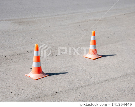 Two orange and white traffic cones on road blocking access safety warning construction zone concept. Two orange and white traffic cones on road blocking access safety warning construction zone concept. 141594449