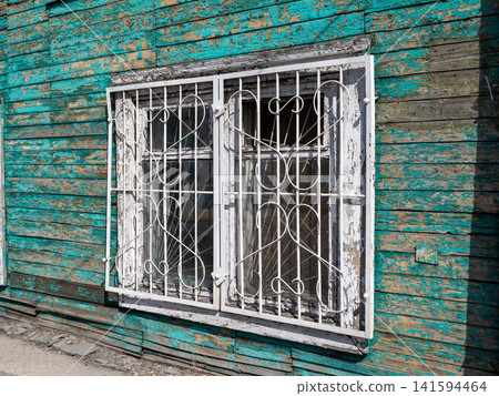 Window with decorative wrought iron grille architectural detail on building facade. 141594464
