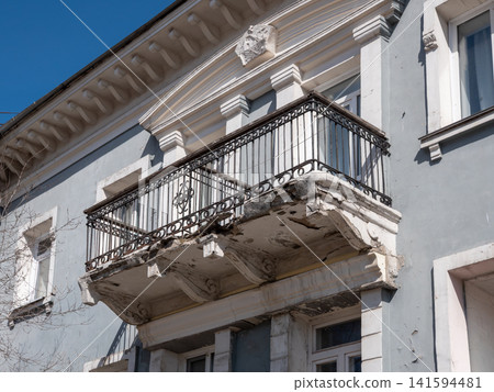 Old vintage balcony in need of restoration weathered architectural detail on building facade. Old vintage balcony in need of restoration weathered architectural detail on building facade. 141594481