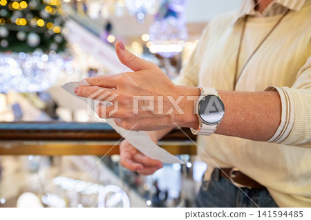 Woman studying long receipt in Christmas shopping mall. Shopper checking paper bill after holiday sale. Consumer reviewing expenses and budget during New Year retail discount season. 141594485
