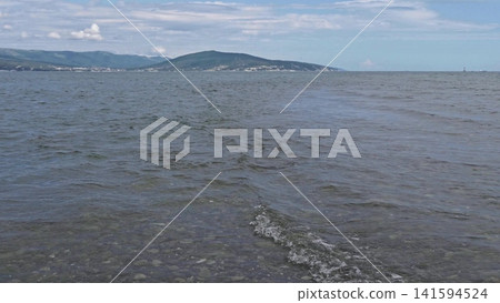 Panoramic view of the sea from a rocky hillside with pine trees under a clear blue summer sky 141594524