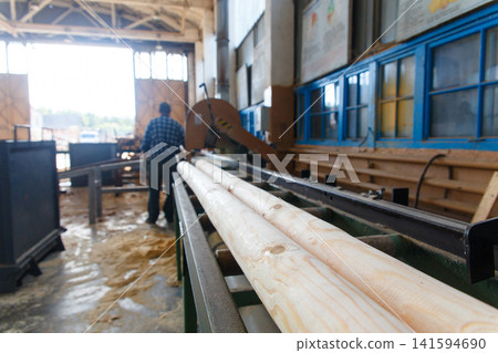 Worker operating wood processing machinery at a sawmill Worker operating wood processing machinery at a sawmill 141594690