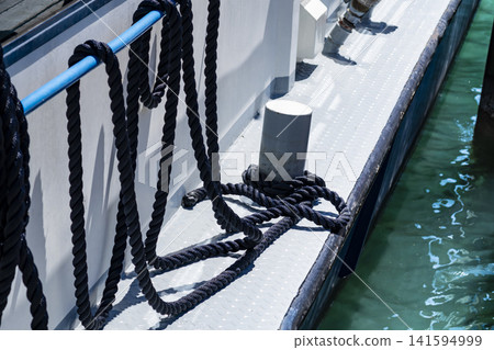 Mooring rope secured to a bollard on a ship deck, illustrating maritime work and dockside responsibilities in waterfront settings. Mooring rope secured to a bollard on a ship deck, illustrating maritime work and dockside responsibilities in waterfront settings. 141594999
