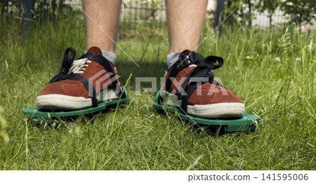 Person using lawn aerator shoes on grass, illustrating practical garden maintenance for healthy turf and soil care in home yards. Person using lawn aerator shoes on grass, illustrating practical garden maintenance for healthy turf and soil care in home yards. 141595006