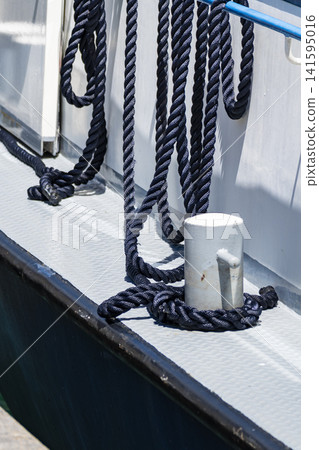 Mooring rope tied to a bollard on a boat deck, illustrating the boat docking and mooring process in practical waterfront settings. Mooring rope tied to a bollard on a boat deck, illustrating the boat docking and mooring process in practical waterfront settings. 141595016
