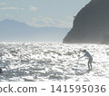 一位遊客在湘南地區享受立式槳板衝浪，欣賞波光粼粼的大海。 141595036