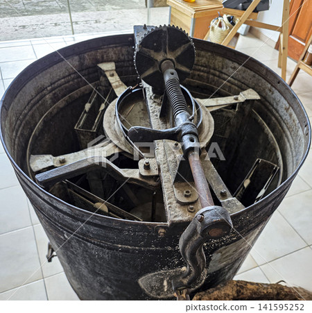 Vintage manual cast iron honey extractor equipment used in traditional beekeeping practice Vintage manual cast iron honey extractor equipment used in traditional beekeeping practice 141595252
