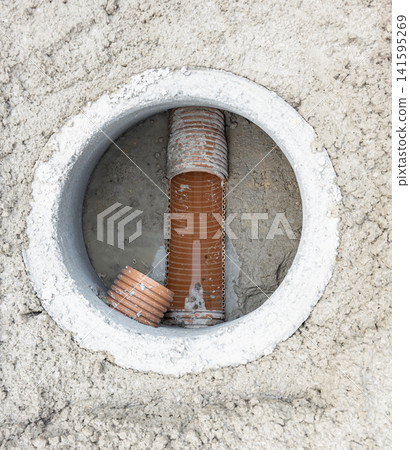High angle view of orange plastic drainage pipes in a concrete inspection manhole shaft High angle view of orange plastic drainage pipes in a concrete inspection manhole shaft 141595269