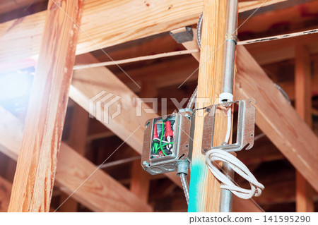 Workers are installing electrical wiring fixtures in new home. tools materials are visible. Workers are installing electrical wiring fixtures in new home. tools materials are visible. 141595290