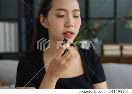 Beautiful Asian woman putting on makeup cosmetic at home. 141595591