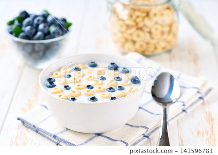 Healthy breakfast with corn rings and blueberry on a white wooden table. Healthy breakfast with corn rings and blueberry on a white wooden table. 141596781