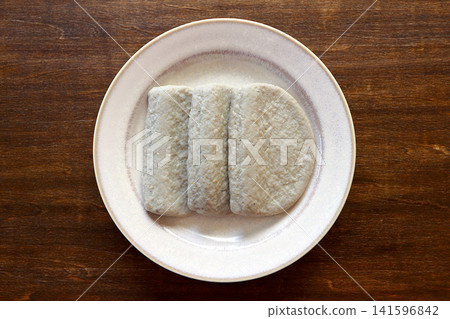 Black fish cake viewed from directly above the table background. Black fish cake viewed from directly above the table background. 141596842