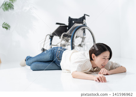A woman in a wheelchair falls over. A woman in a wheelchair falls over. 141596962