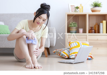 一位女士在客廳為自己做足部按摩。 141597298