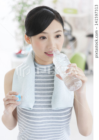 A woman rehydrating during her workout. A woman rehydrating during her workout. 141597313