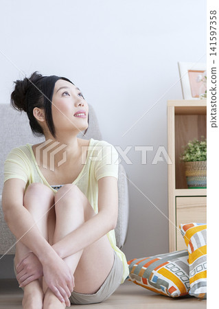 A woman sitting on the floor, deep in thought. A woman sitting on the floor, deep in thought. 141597358