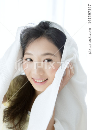 A woman wiping her hair with a towel. A woman wiping her hair with a towel. 141597367