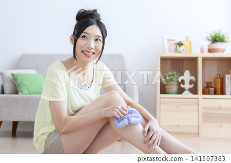 一位女士在客廳為自己做足部按摩。 141597383