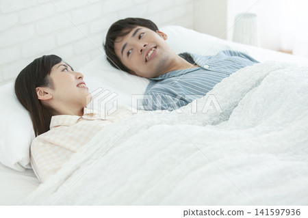 一對穿著睡衣的情侶在床上聊天。 141597936
