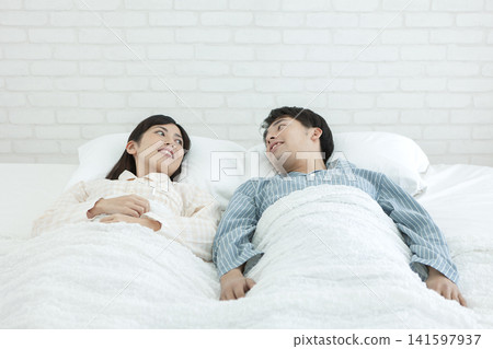 一對穿著睡衣的情侶在床上聊天。 141597937