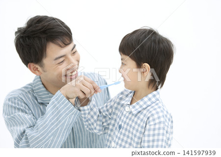 A parent and child in pajamas brushing their teeth. 141597939