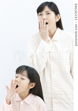 一位家長和孩子穿著睡衣打哈欠。 141597949