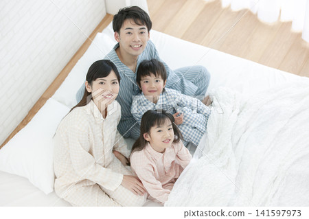 一家人穿著睡衣坐在床上。 141597973