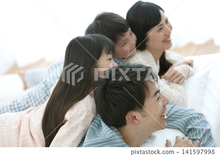 A family in pajamas lying on a bed 141597998