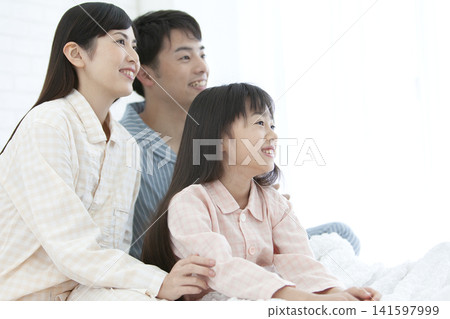 一家人穿著睡衣坐在床上。 141597999