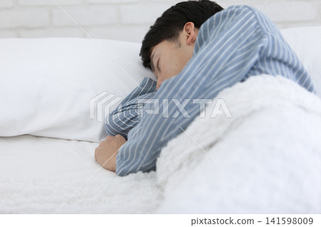 A man in pajamas sleeping in a bed. A man in pajamas sleeping in a bed. 141598009