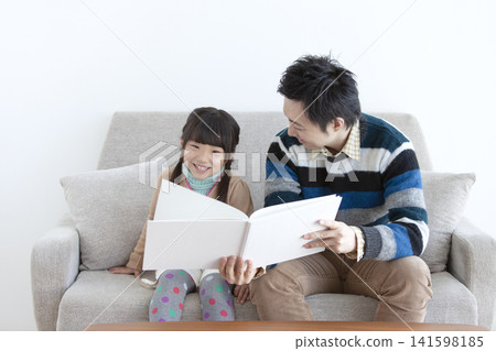 Parents and children looking at books on the sofa Parents and children looking at books on the sofa 141598185