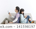 A couple looking at their cell phones on the sofa 141598197