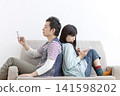 A couple looking at their cell phones on the sofa 141598202