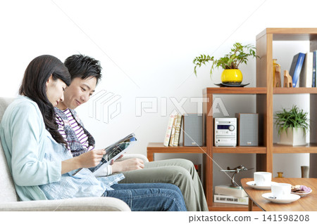 A couple reading a book on the sofa A couple reading a book on the sofa 141598208