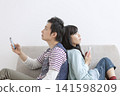 A couple looking at their cell phones on the sofa 141598209
