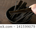 Close-up of a piece of kelp being held between fingers. 141599079
