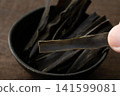 Close-up of a piece of kelp being held between fingers. 141599081