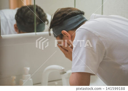 一名四十多歲的男子戴著髮帶，在水槽邊洗臉。 141599188