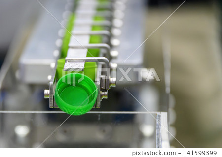 Green plastic bottle caps on conveyor belt after mass production process Green plastic bottle caps on conveyor belt after mass production process 141599399