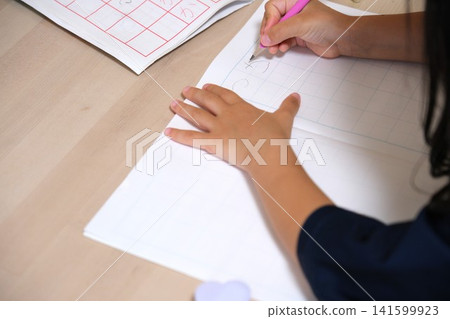 一個孩子正在用鉛筆在筆記本上練習寫平假名。 一個孩子正在用鉛筆在筆記本上練習寫平假名。 141599923