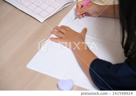 孩子的小手用鉛筆在筆記本上寫平假名。 孩子的小手用鉛筆在筆記本上寫平假名。 141599924