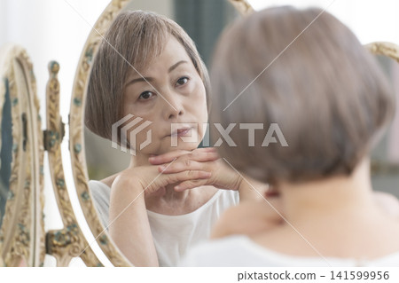 Senior woman doing her skincare routine in front of the mirror Senior woman doing her skincare routine in front of the mirror 141599956