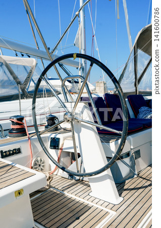Helm station and cockpit of a modern sailing yacht moored in a marina. Concept of sailing, navigation, travel, freedom, adventure and luxury lifestyle Helm station and cockpit of a modern sailing yacht moored in a marina. Concept of sailing, navigation, travel, freedom, adventure and luxury lifestyle 141600786
